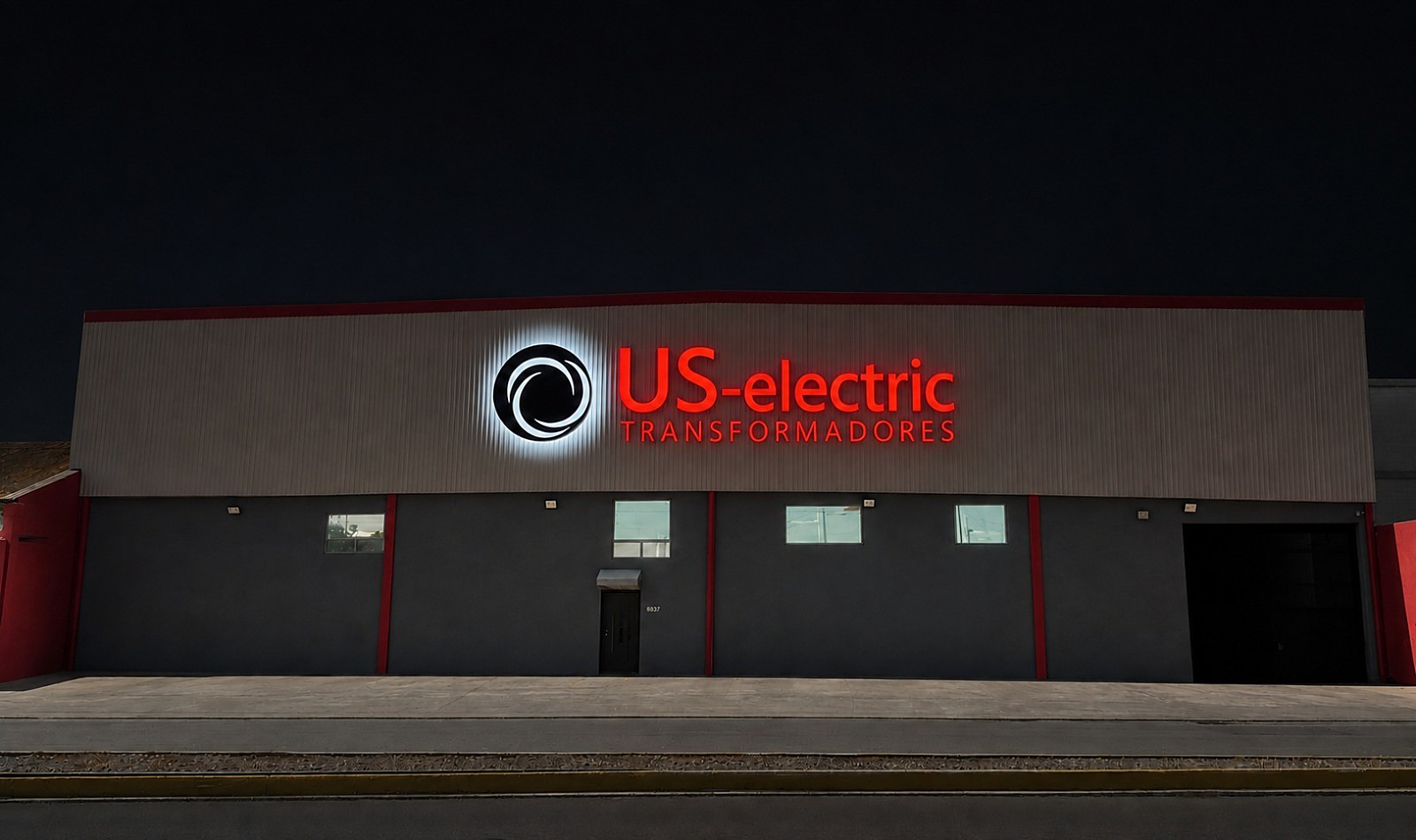 Fachada de planta US Electric de noche, con letrero iluminado — Guadalupe, N.L.